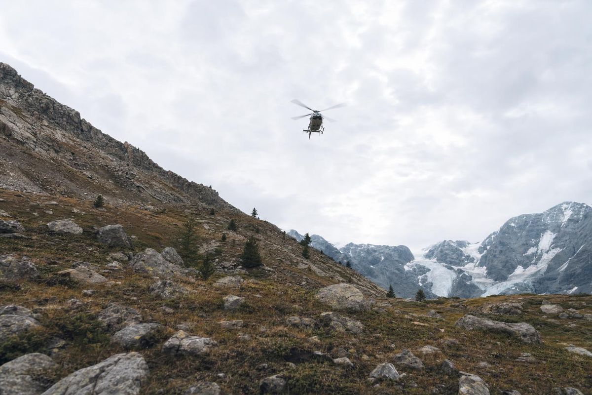 Rettungshubschrauber im Anflug über einem Bergkamm, noch klein am Himmel