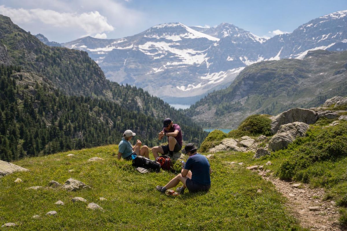 Wandergruppe macht Pause an einem Bergweg, einer schaut auf die Uhr