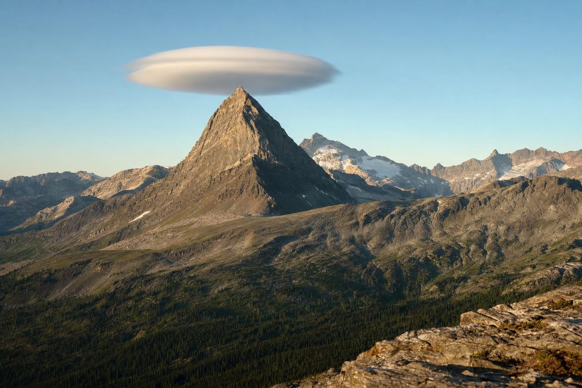 Linsenförmige Föhnwolke steht unbewegt über einem Gipfelkamm, klarer Himmel darunter