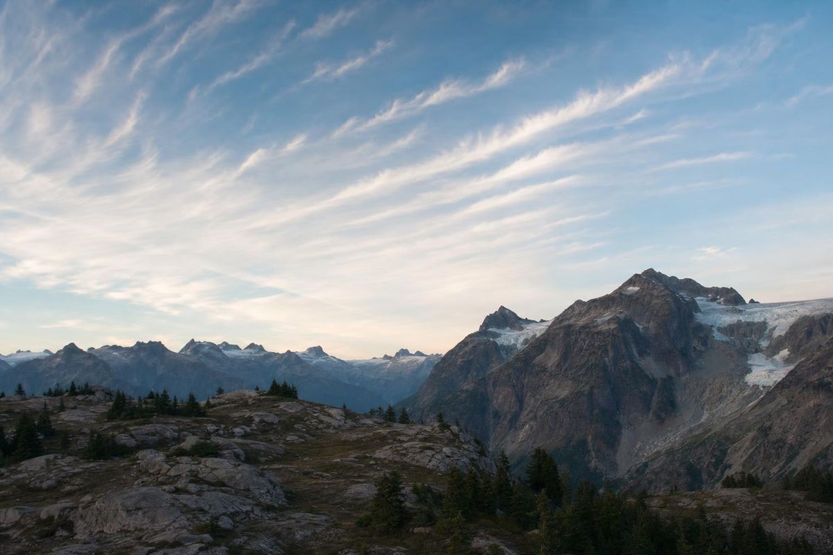 Dünne Zirruswolken ziehen hoch über einem Bergkamm