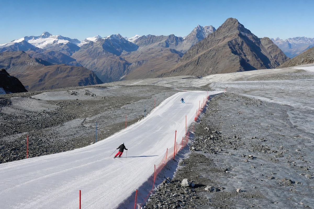Schmale präparierte Piste auf einem Gletscher, am Rand Stangen und eine Absperrung, daneben graues Eis