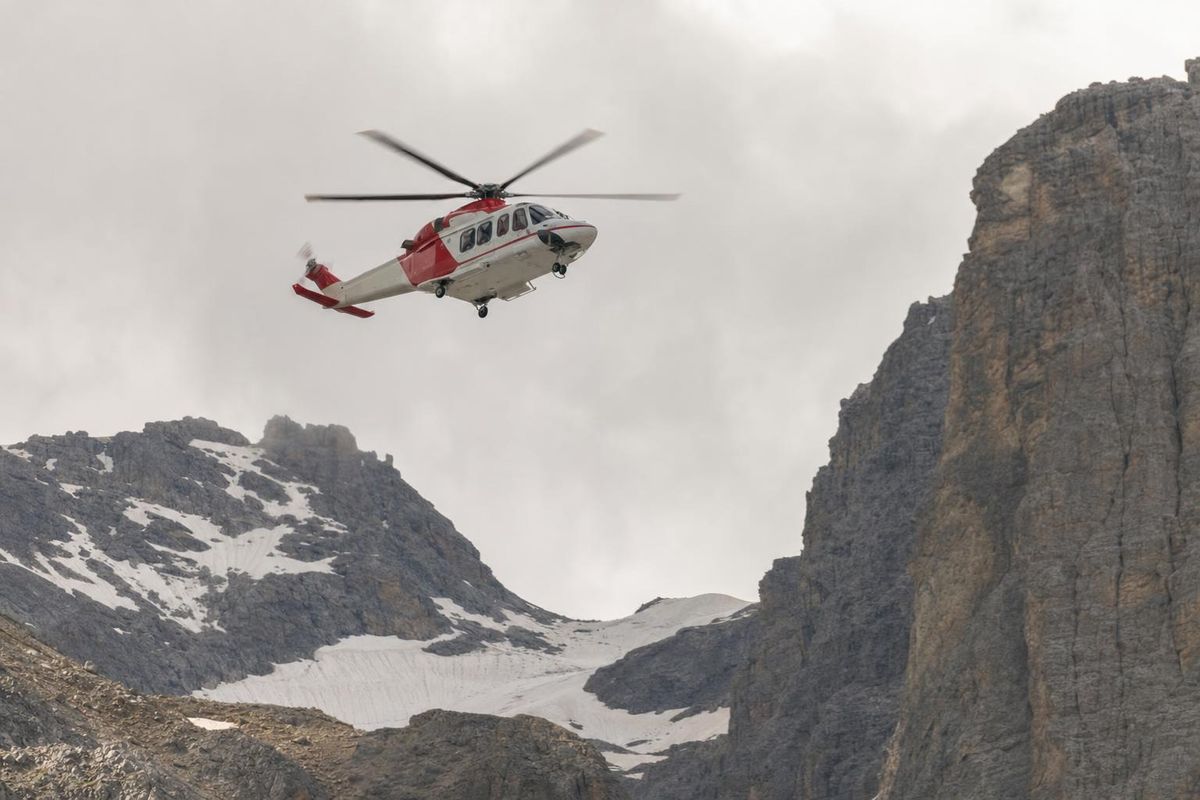 Rettungshubschrauber über einem felsigen Bergkessel, aus der Ferne gesehen